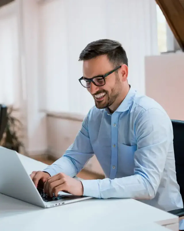 A business user smiling while using a laptop